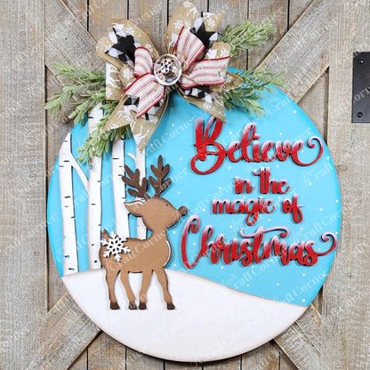 The "Oh Deer Door Hanger" by Janet's Craft Corner is a beautifully hand-painted round Christmas sign showcasing a reindeer surrounded by snowflakes and birch trees, with the phrase "Believe in the magic of Christmas" elegantly written in red script. It's ideal for home décor, accented with pine branches and a festive bow to add a personalized touch to your holiday spirit.