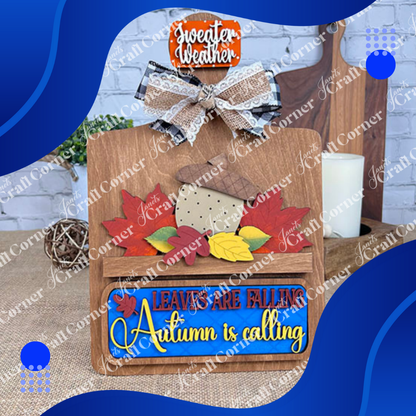 Autumn-themed decorative sign with leaves and text on a wooden board.