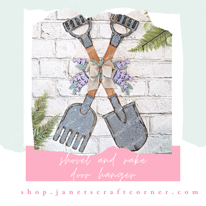 A lavender-accented wood decor with crossed shovel and rake, adorned with a bow on a white brick wall. Fern leaves surround this DIY project featuring "Shovel and Rake Door Hanger" and "NEW ON MY YOUTUBE" text next to a play button icon. Check out Janet's Craft Corner for this seasonal craft kit!.