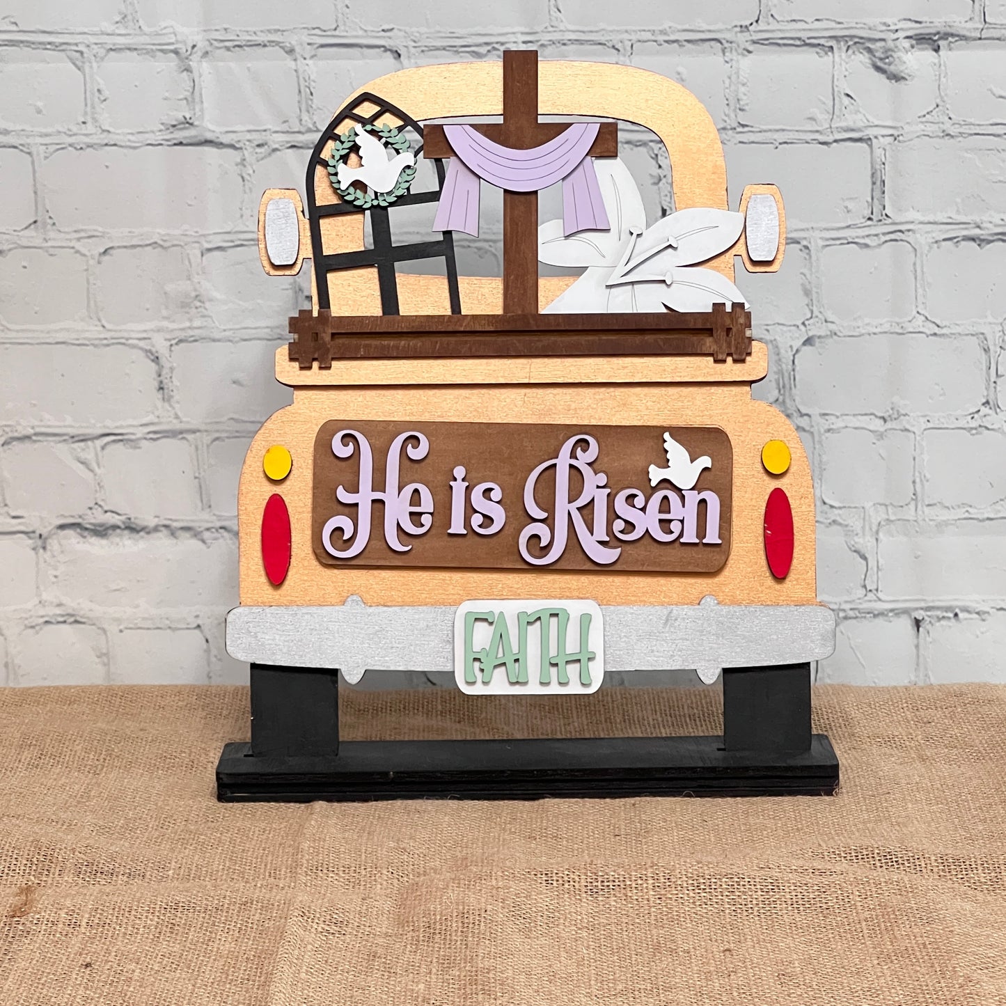 Janet's Craft Corner offers the Antique Truck Base with Insert, a DIY interchangeable home decor kit. Featuring "He is Risen" in purple letters, a cross, window wreath, and "FAITH" on the bumper, it adds a spiritual touch to any rustic setting. Ideal for enhancing your home decor.