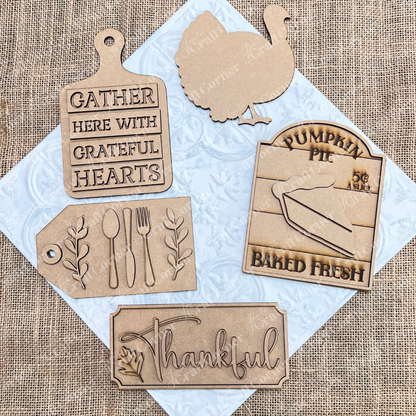 The Thankful Decor Set by Janet's Craft Corner is a delightful DIY home decor craft kit that features fall-themed wooden cutouts on a burlap background. This set includes five pieces: a cutting board with the phrase "Gather here with grateful hearts," a turkey, a pumpkin pie sign, a utensil tag, and a "Thankful" plaque adorned with a leaf—ideal for enhancing your seasonal home décor.