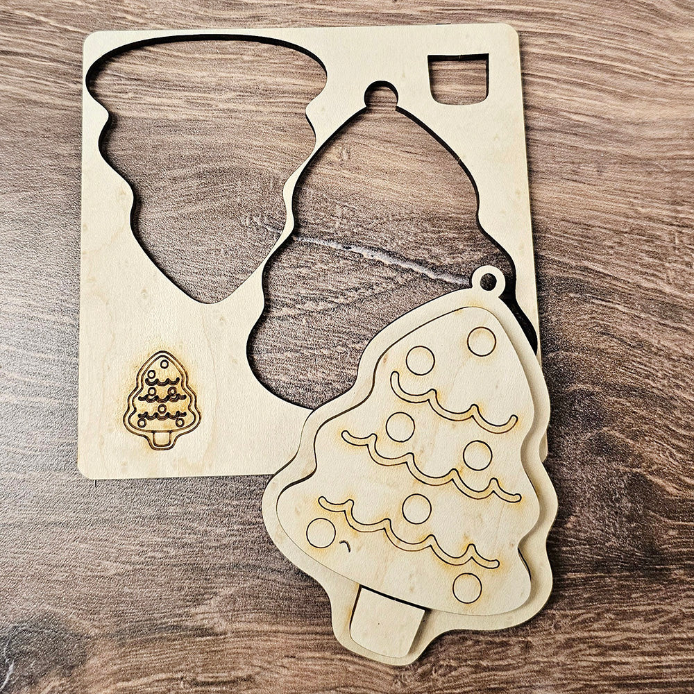 A wooden Christmas tree ornament, reminiscent of Janet's Craft Corner's Sugar Cookie Ornaments DIY Decoration Kit, sits next to its matching cut-out within a wooden stencil. The ornament showcases circular decorations and wavy lines, similar to sugar cookie designs, while the stencil rests on a wooden surface.