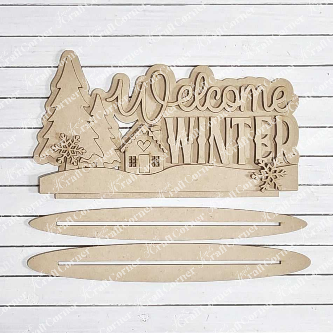 Introducing the "Welcome Winter Word Art" from Janet's Craft Corner: This hand-painted wooden sign features the phrase "Welcome Winter" surrounded by trees, a house, and snowflakes on a white background. Ideal for enhancing your home décor, it includes two separate slats below the main sign for an added charming touch to any space.