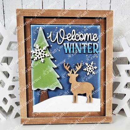 Janet's Craft Corner presents a charming Farmhouse Frame for Interchangeable Signs, featuring a snowy scene with a green tree, tan deer, and white snowflakes on blue. "Welcome Winter" appears in elegant letters. The wooden frame adds rustic charm, ideal for DIY home decor craft projects.