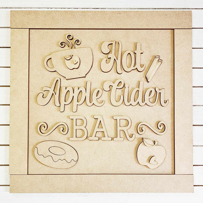 The Apple Cider Bar Sign Shelf Sitter from Janet's Craft Corner features a charming wooden design with a steaming cup, cinnamon sticks, a donut, and an apple on a light wooden background. This delightful home décor piece is perfect for an Apple Cider Bar setup or as part of your DIY craft kit.