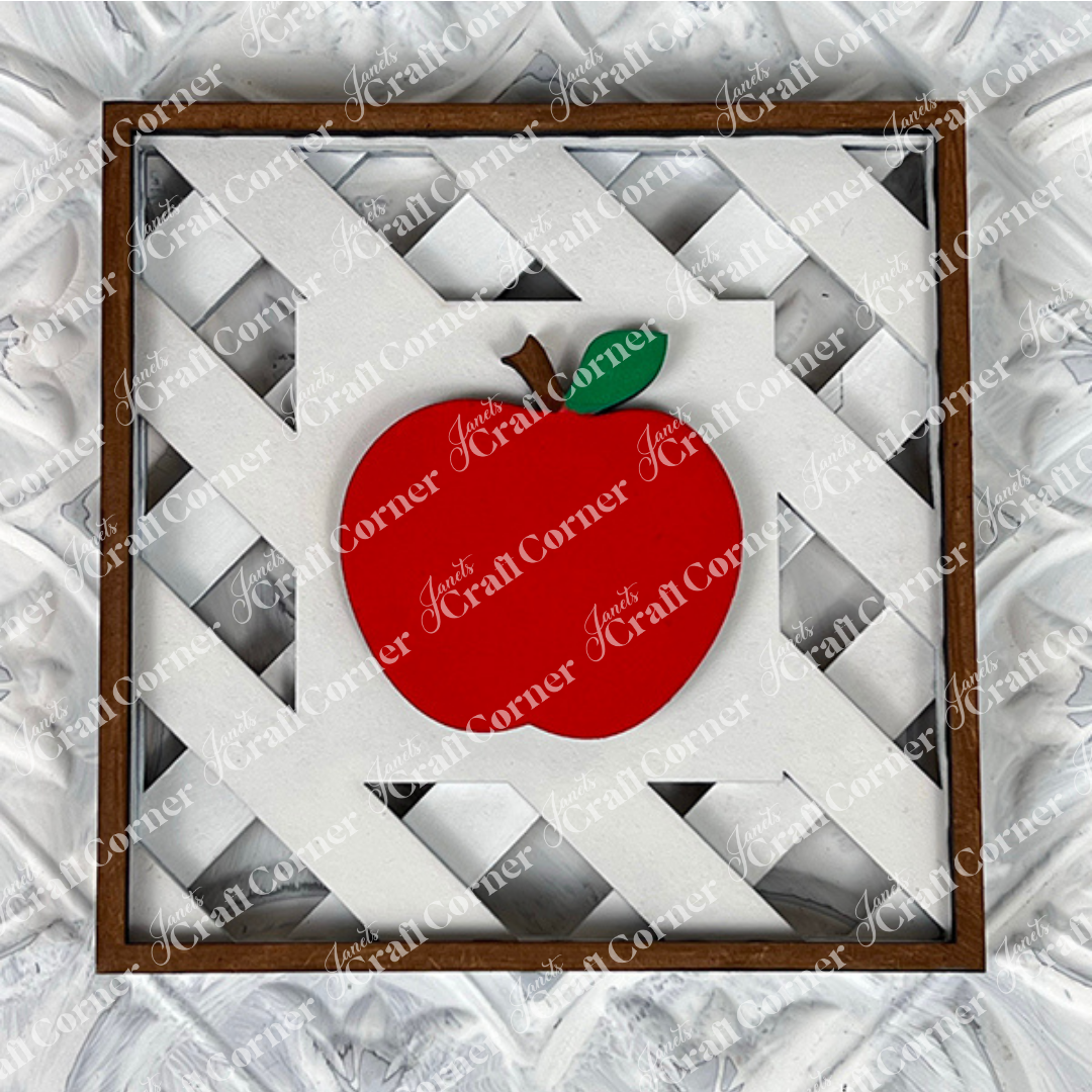 Janet's Craft Corner Apple on Lattice Square: Framed artwork with a bright red apple, green leaf, and brown stem on a white lattice background in a wooden border—ideal for DIY home decor or seasonal craft kits.