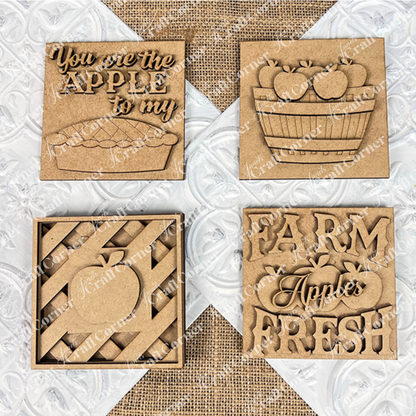 Janet's Craft Corner Apple Swappable Squares DIY kit includes four wooden signs with apple cut-outs: "You are the apple to my pie," a basket, a striped apple, and "Farm Fresh Apples." Perfect for seasonal home decor.