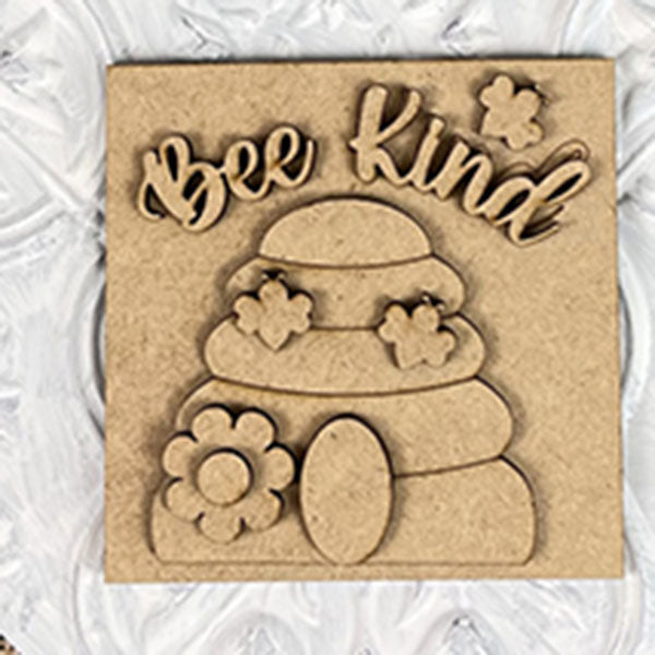 The Bee Swappable Squares by Janet's Craft Corner features "Bee Kind" above a beehive with flowers and a bee, handmade for charming home decor on a textured white background.