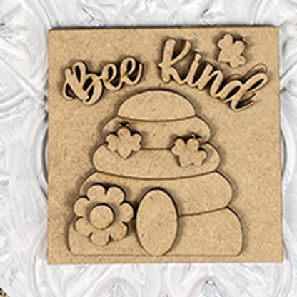The Bee Swappable Squares by Janet's Craft Corner features "Bee Kind" above a beehive with flowers and a bee, handmade for charming home decor on a textured white background.