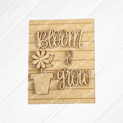 Janet's Craft Corner Spring Switchable Farmhouse Signs DIY kit features a wooden sign with a potted flower and “Bloom & Grow” in raised script on a lined background—perfect for tiered tray decor.