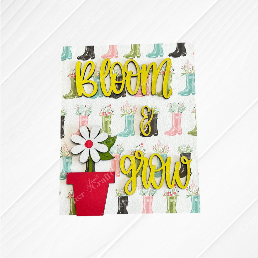 Janet's Craft Corner’s Spring Switchable Farmhouse Signs DIY kit features a card with colorful rain boots holding flowers, “bloom & grow” in yellow script, and a white daisy in a red pot—perfect for tiered tray displays.