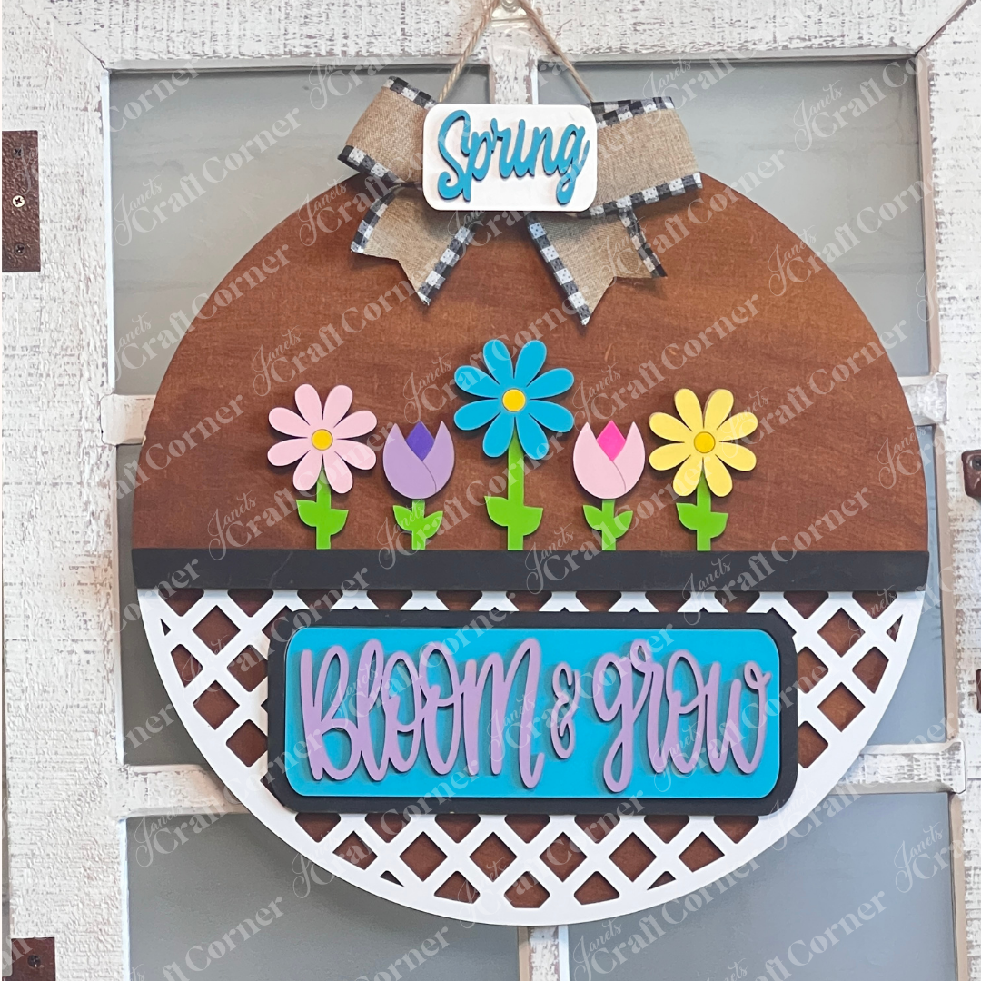 Janet's Craft Corner offers the "Bloom & Grow Interchangeable Insert," a DIY home decor kit with vibrant flowers and text, complemented by a checkered bow and "Spring Blooms" tag, perfect for adding life to your space against any backdrop.