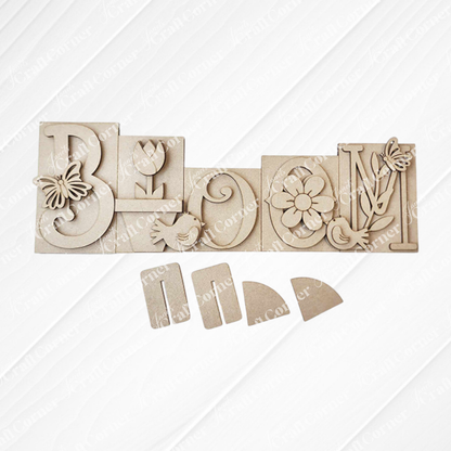 Introducing the "Bloom Word Block Shelf Sitter" from Janet's Craft Corner. This DIY home decor kit features a wood sign with carved letters: butterfly on "B," tulip on "L," bird on "O," flower on the second "O," and leaves with a bird on "M." Easy to assemble for seasonal decor.