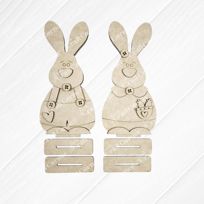 Janet's Craft Corner Bunny Couple Shelf Sitters—DIY seasonal home decor craft kit (set of 2)—features unfinished wooden bunnies with button details, a heart, and a carrot pocket; ideal for spring decorating or crafting at home.