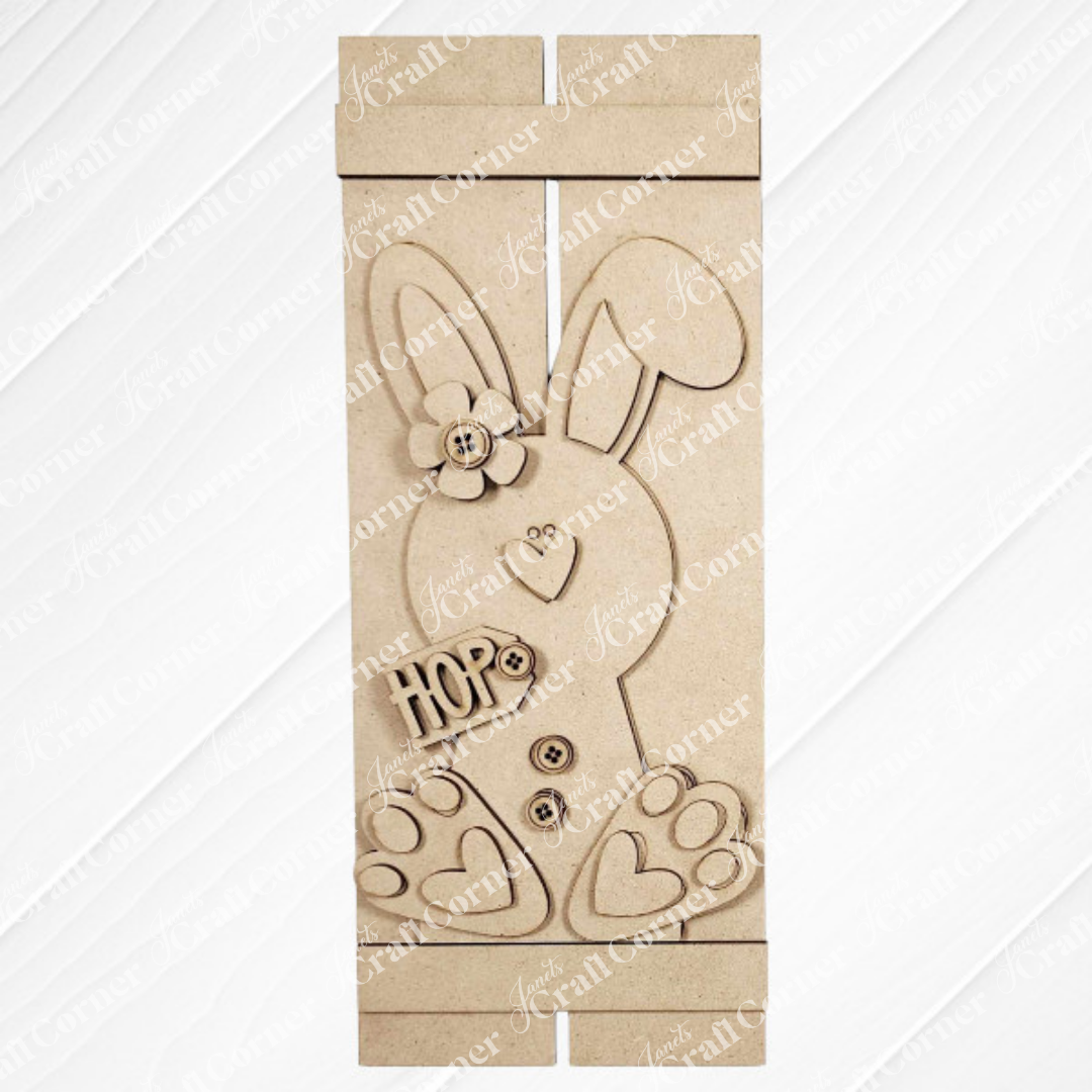 The Bunny Table Top Pallet by Janet's Craft Corner is a charming DIY home decor craft kit featuring a wooden bunny with a flower, buttons, and heart-shaped foot details. Displayed on a white textured surface, it spells "HOP" and makes an ideal shelf leaner.