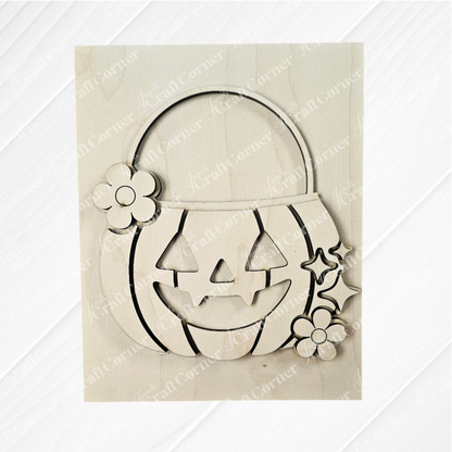 The Halloween Farmhouse Signs from Janet's Craft Corner feature a wooden jack-o'-lantern cutout with smiling face, floral accents, and handle—perfect DIY seasonal home decor for your tiered tray, shown on a light wooden background.