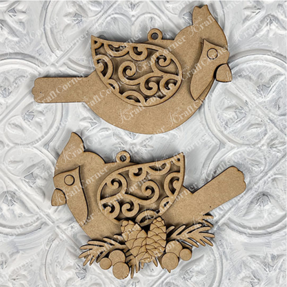 The Cardinal Ornament DIY craft kit from Janet's Craft Corner offers two design choices and includes a set of one. Perfect for holiday décor, these ornaments feature intricate swirls on their wings, a hanging loop, and embellishing pinecones and leaves for festive charm.