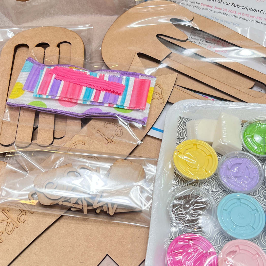 A Crafted by You! Subscription DIY home decor craft kit from Janet’s Craft Corner sits on the table, filled with wooden cutouts, colorful ribbon, and paint—perfect inspiration for your creative community.