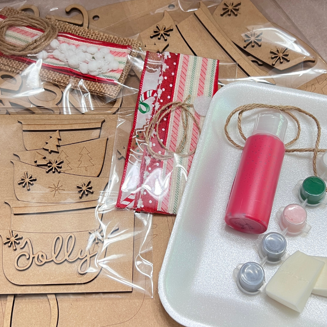 The Crafted by You! Subscription by Janet's Craft Corner is a monthly DIY home decor kit with wooden cutouts, paint, a brush, a foam sponge, fabric, and trims—perfectly packaged for creative holiday crafting.