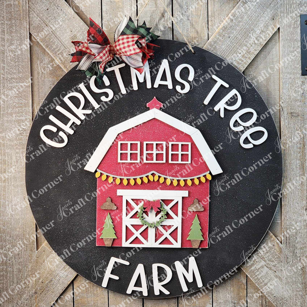 The Christmas Tree Farm Door Hanger DIY Decor Kit by Janet's Craft Corner includes a round sign with a charming wooden texture background, featuring a festive red barn decorated with Christmas trees and a wreath, surrounded by the words "Christmas Tree Farm." It is topped with a red and white plaid bow, making it perfect for home décor projects.