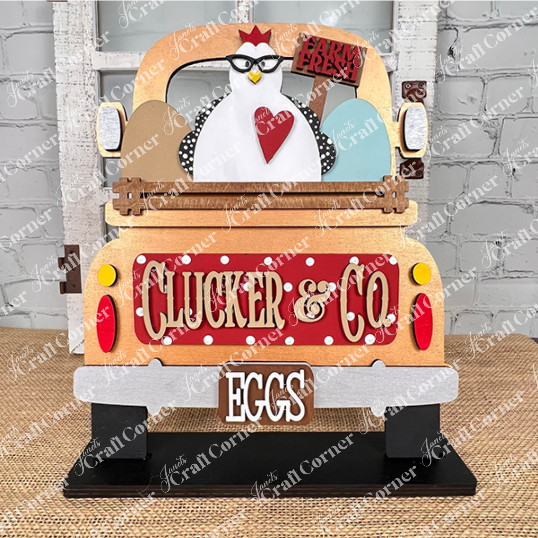 A decorative sign from Janet's Craft Corner, the Clucker & Co. Interchangeable Insert - Painted, features a vintage truck design with a charming chicken motif sporting glasses. The truck is adorned with the "Clucker & Co." and "EGGS" labels, highlighted by a heart symbol and three large eggs beneath a "Farm Fresh" banner, adding rustic charm to any space. This piece elegantly brings interchangeable craft inserts to life.