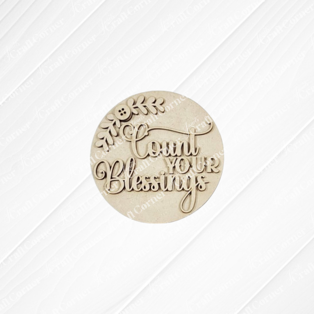 Janet’s Craft Corner Heirloom Decor Set features a round beige plaque with “Count Your Blessings” in decorative script and a leafy branch—ideal as a seasonal DIY project in this versatile home decor craft kit.