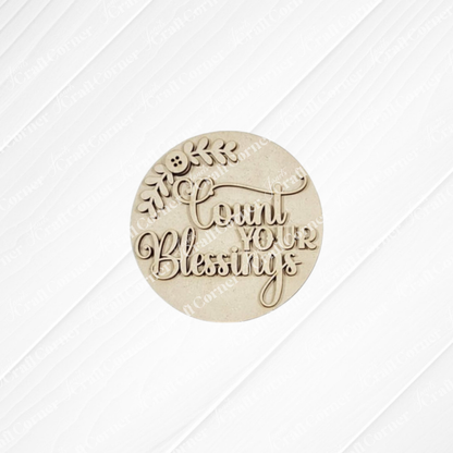 Janet’s Craft Corner Heirloom Decor Set features a round beige plaque with “Count Your Blessings” in decorative script and a leafy branch—ideal as a seasonal DIY project in this versatile home decor craft kit.