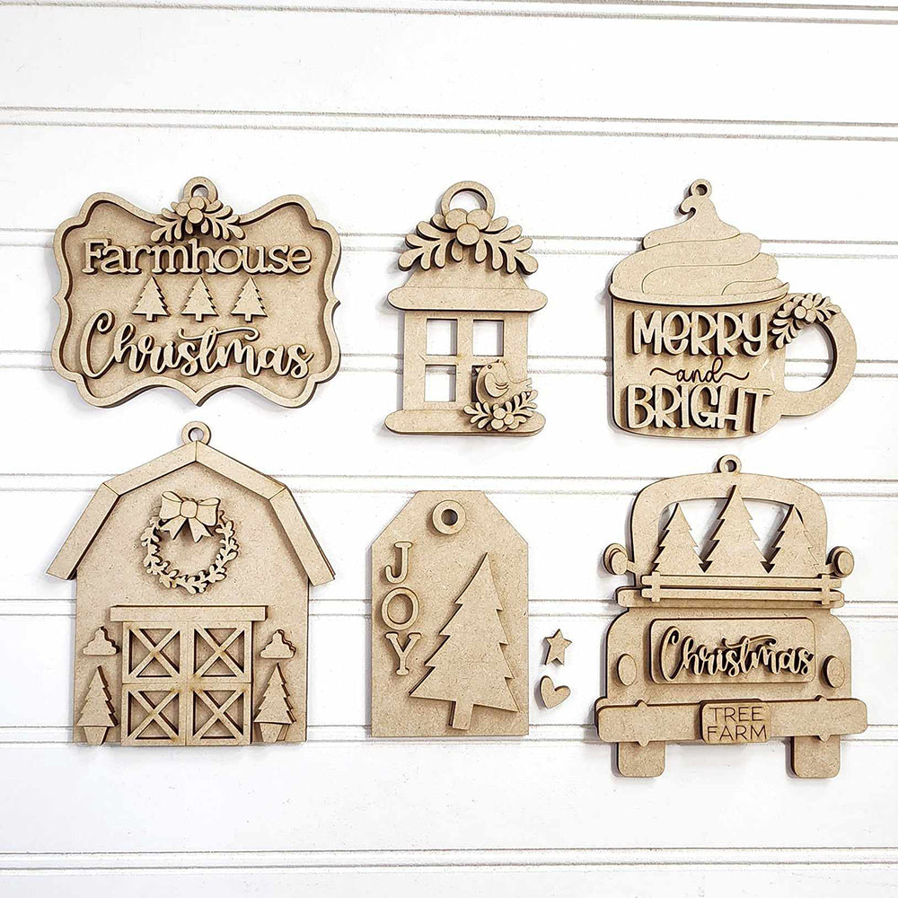 Janet's Craft Corner presents the Country Christmas Ornaments - Set of 6 and DIY Decoration Kits, featuring wooden ornaments on a white background. Perfect for home décor, this collection includes delightful designs such as a farmhouse sign, candle, and cup with "Merry and Bright," as well as festive mistletoe ornaments. Unleash your creativity with the DIY craft kits that include charming elements like barns, gift tags labeled "Joy," and trucks decorated with trees.