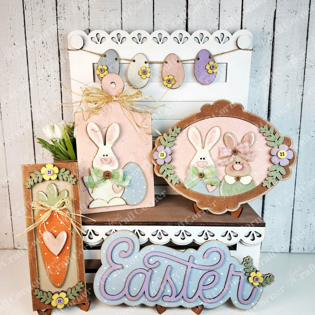 Janet's Craft Corner's Easter Decor Set is a DIY seasonal home decor kit with 5 handcrafted pieces—bunny, eggs, carrot, flowers, and "Easter" sign in pastels—all set against a white wooden background.