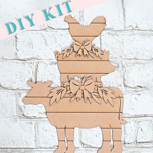 Introducing the Farm Animal Stacker Shelf Sitter from Janet's Craft Corner—a delightful DIY home décor project. This kit features wooden cutouts of a cow, pig, and chicken stacked vertically, each with a decorative bow and foliage. The display is set against a white brick wall with "DIY KIT" in pastel colors at the top.