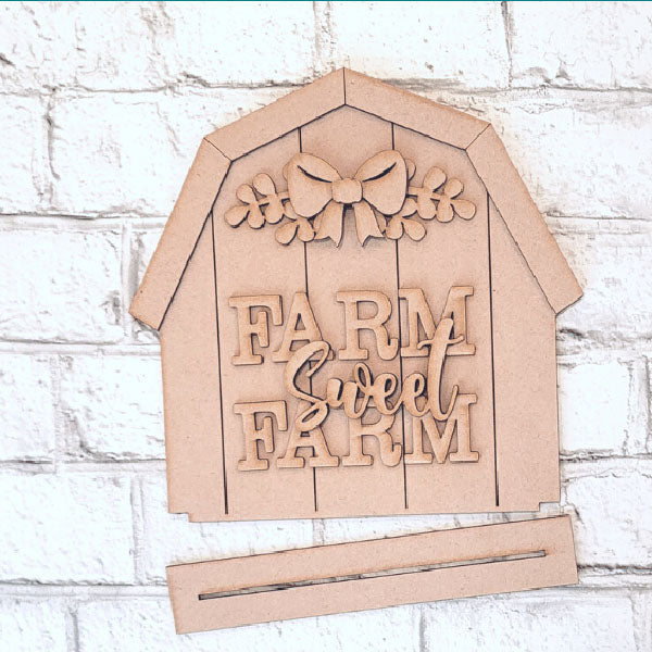 Add farmhouse charm with the "Farm Sweet Farm Shelf Sitter" from Janet's Craft Corner. This DIY craft kit features a wooden cutout barn, accented by a bow and leaves, perfect for adding rustic flair to your home decor.