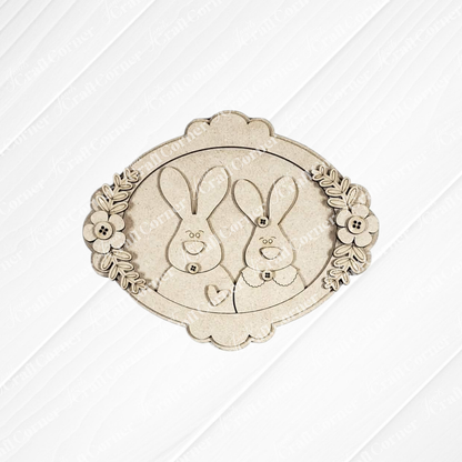 Janet's Craft Corner Framed Bunny Couple Door/Wall Hanger DIY kit includes a laser-cut plaque with button, bow tie, and heart details in a floral oval frame—ideal for seasonal home decor or as a charming craft project. Set of 1.