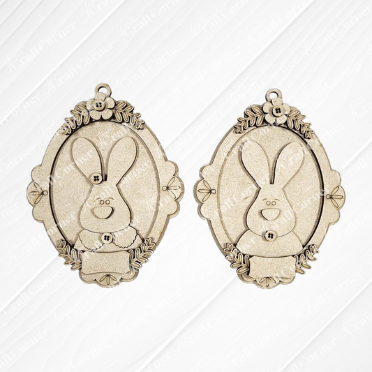 Janet's Craft Corner Framed Easter Bunny Basket Tags are two ornate, oval pendants with floral details and smiling bunny faces—ideal as personalized Easter décor or for DIY craft kits.