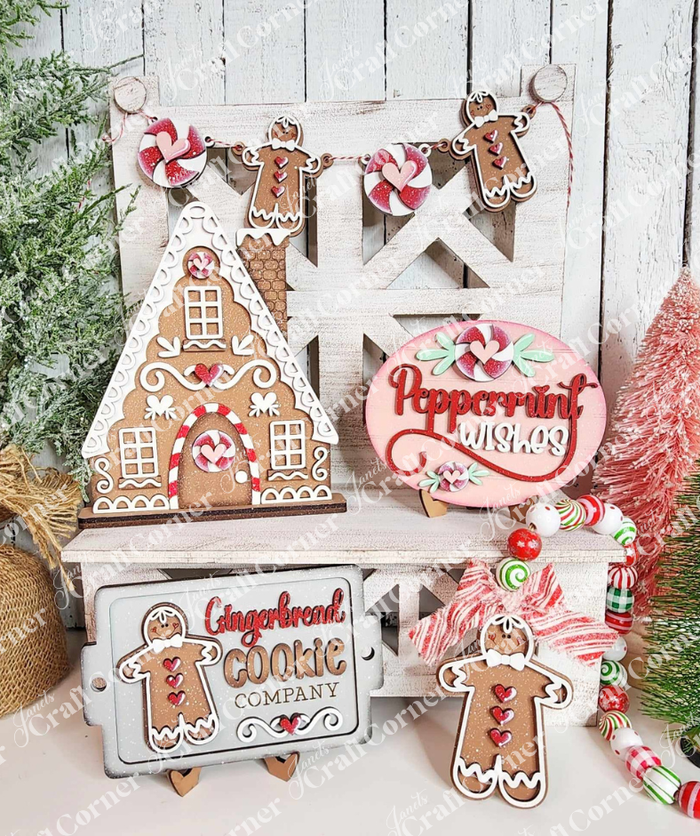 Create a cozy holiday atmosphere with Janet's Craft Corner's Gingerbread Decor Set - 5 pieces. This DIY home decor craft kit features a festive scene complete with a gingerbread house, cookies, and charming signs that read "Peppermint Wishes" and "Gingerbread Cookie Company," all adorned with candy canes and greenery.