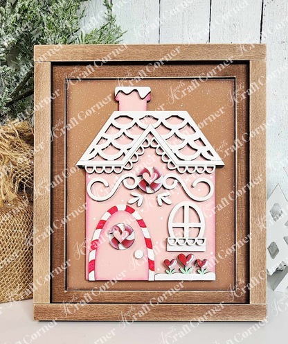 A painted sample of the Gingerbread House Switchable Farmhouse Sign and Farmhouse frame from Janet's Craft Corner's displayed against a white shiplap wall. The Gingerbread Switchable Farmhouse Sign features a cute house with red & white peppermint and white icing trim on a cinnamon background in a wooden frame—ideal for seasonal home decor. 