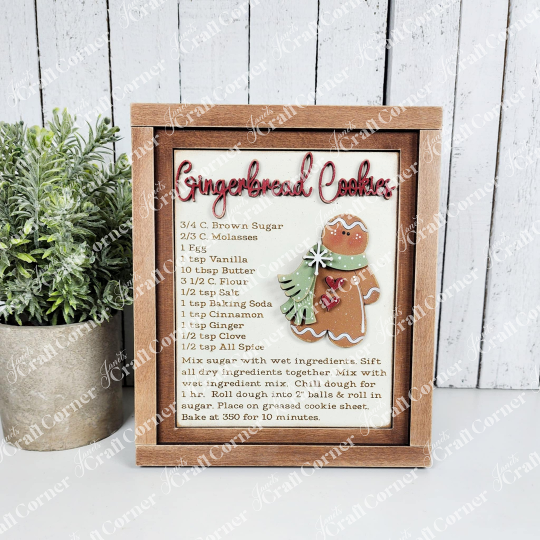 Framed gingerbread cookie recipe with decorative elements on a wooden surface.