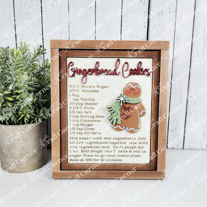 Framed gingerbread cookie recipe with decorative elements on a wooden surface.