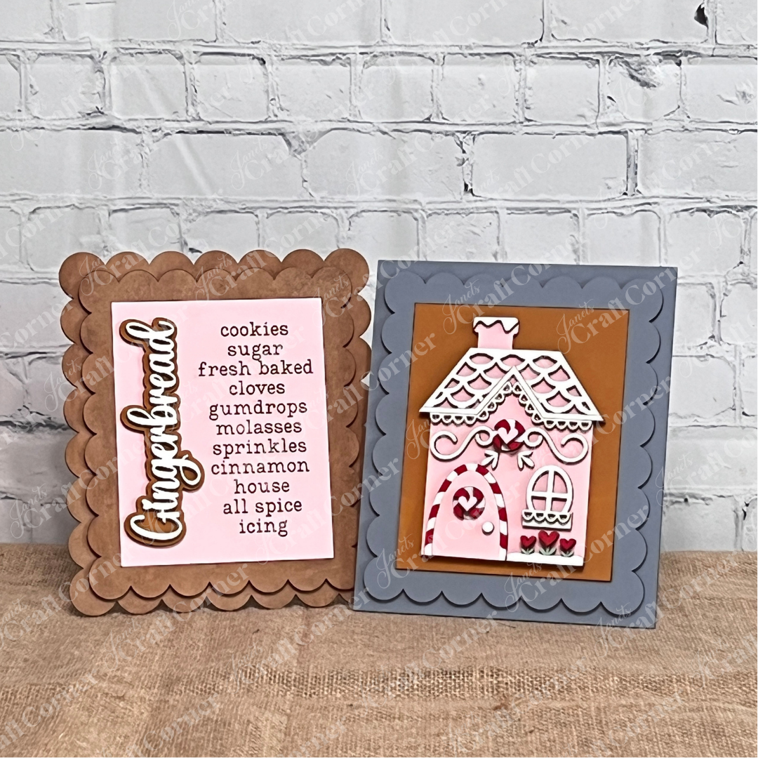 Janet's Craft Corner Single Scallop Trim Farmhouse Frames display gingerbread-themed words and a pink icing gingerbread house, creating a charming interchangeable accent on a wooden surface against a white brick wall.