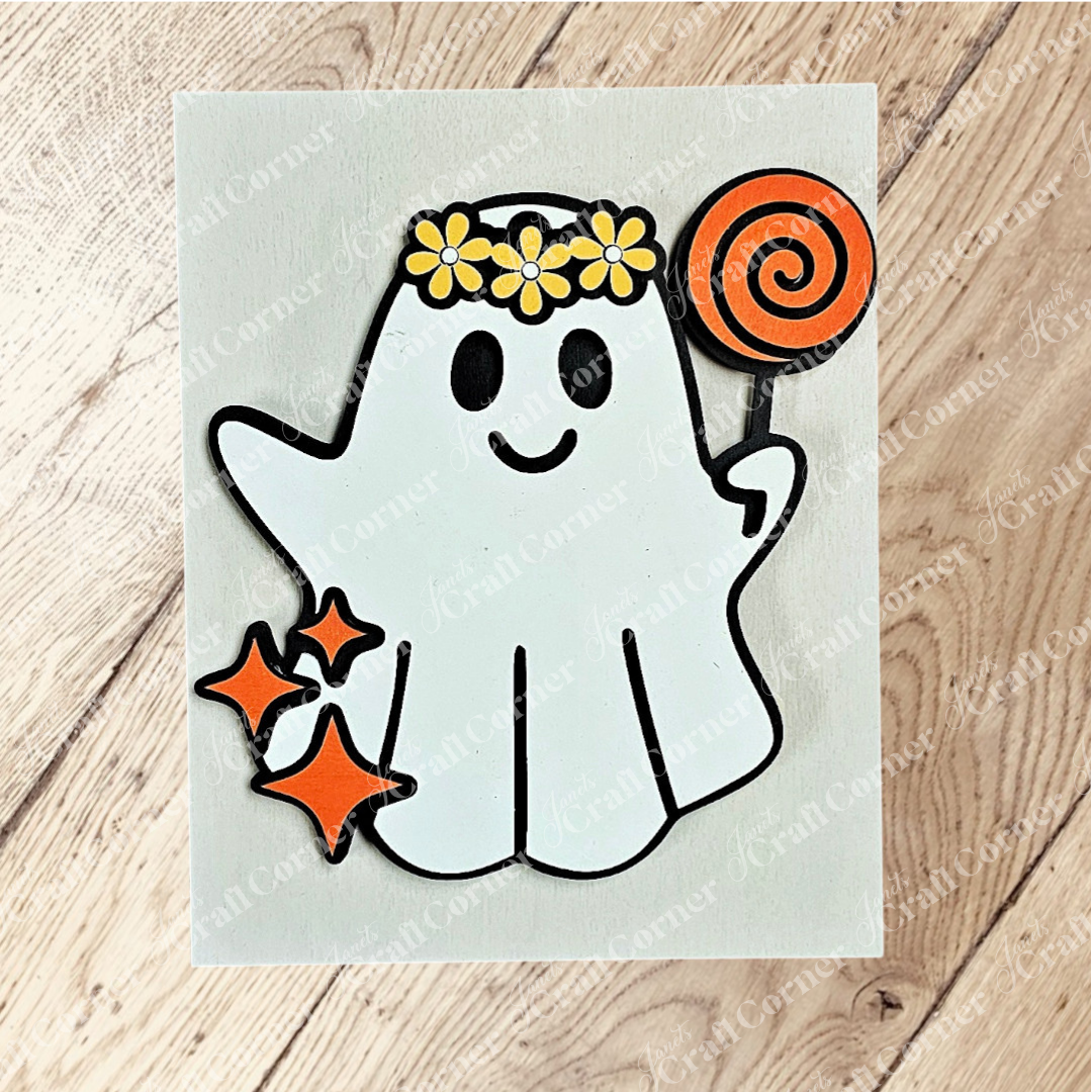 Janet's Craft Corner Halloween Farmhouse Signs feature a cute cartoon ghost with a flower crown, holding an orange lollipop and surrounded by sparkles on a light wood background—ideal for tiered tray displays or seasonal DIY decor.