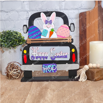 The Happy Easter Bunny Interchangeable Insert from Janet's Craft Corner is a DIY home decor kit with 3 pieces, featuring a truck with a bunny, colorful eggs, and carrot. Adorned with "Happy Easter" and "Hop," it's perfect against a light brick wall backdrop.