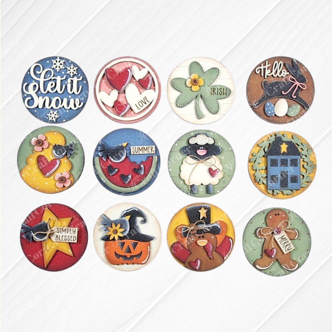 The Saltbox House Round Display by Janet's Craft Corner is a DIY seasonal home decor craft kit set of 1, featuring festive designs like "Let it snow," hearts, clover, sheep, star, witch hat, gingerbread man, and "Warm Wishes.