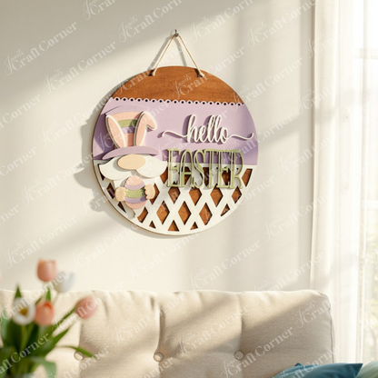 This enchanting wall decoration from Janet's Craft Corner, the Hello Easter Gnome Wall Hanger, features an adorable gnome sporting a vibrant hat and holding an egg. The phrase "Hello Easter" stands out in purple and green hues against a soft pastel background, finished with a charming lattice design—making it an ideal springtime accent for your home decor. Shown hanging on a wall in a family room.
