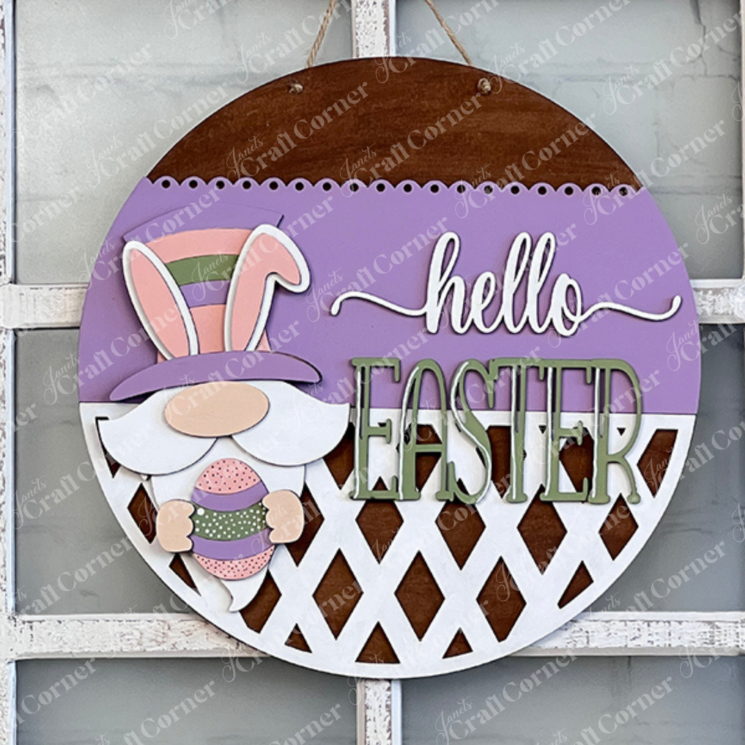 This enchanting wall decoration from Janet's Craft Corner, the Hello Easter Gnome Wall Hanger, features an adorable gnome sporting a vibrant hat and holding an egg. The phrase "Hello Easter" stands out in purple and green hues against a soft pastel background, finished with a charming lattice design—making it an ideal springtime accent for your home decor.