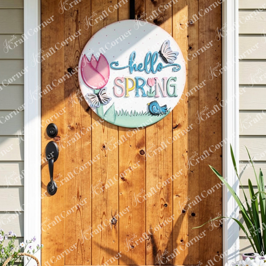 Add a touch of seasonal charm to your home's décor with Janet's Craft Corner's "Hello Spring" Round Door Hanger. This delightful DIY kit features vibrant letters, a tulip, butterflies, and a bird resting on grass. It easily hangs against a wooden door with a  plant nearby, making it the perfect addition for welcoming springtime.