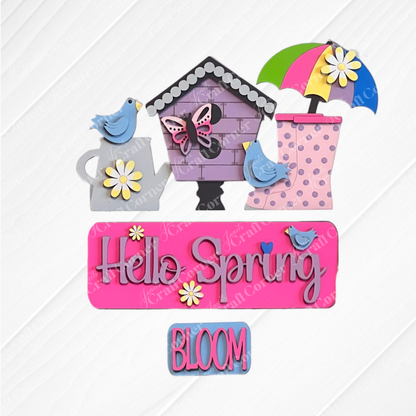 Complete your textured surface with vibrant spring-themed decorations from Janet's Craft Corner. The scene includes a birdhouse, bluebirds, an umbrella, and rain boots. A charming sign displays "Hello Spring" in purple adorned with flowers. This delightful setup is part of the Hello Spring Interchangeable Insert DIY home decor kit, featuring an additional option that says "BLOOM.