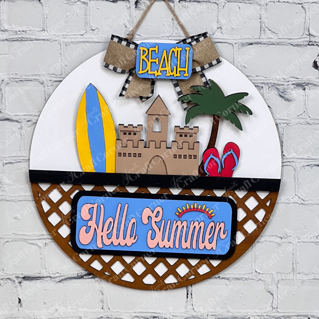 Introducing the Summer Beach Interchangeable Insert, a DIY home decor kit from Janet's Craft Corner. This wooden summer-themed decoration showcases a delightful sandcastle, surfboards, and palm trees, all sitting on a white door hanger with wooden lattice work. The sign displays "Hello Summer" in colorful letters, making it an ideal piece for adding a vibrant touch to your space.