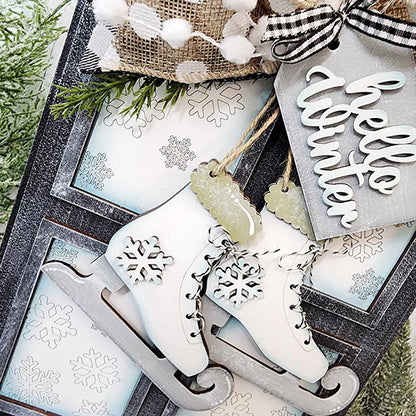 Introducing the "Hello Winter Window Hanger" by Janet's Craft Corner—a captivating festive winter decoration. This DIY kit features a pair of white ice skates embellished with snowflake designs, accompanied by a charming "Hello Winter" sign and sprigs of pine branches. The background displays elegant snowflake patterns, creating a cozy wintry atmosphere for your home decor. An ideal choice for anyone seeking to add an inviting touch to their seasonal decor projects.