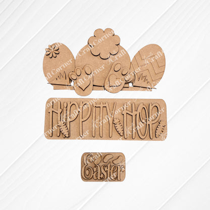 The "Hippity Hop Bunny Butt Interchangeable Insert" by Janet's Craft Corner is a charming hand-painted Easter sign on burlap featuring a bunny, patterned eggs, "HIPPITY HOP" with carrots, and "Easter" on a white diamond texture, perfect for DIY crafters seeking versatile home decor.