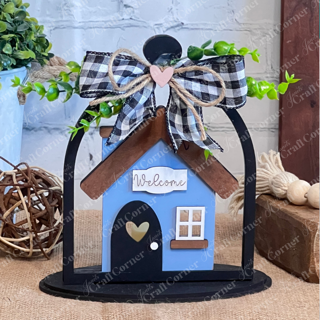 The Home Cloche Votive Holder Shelf Sitter from Janet's Craft Corner is a DIY home decor craft kit, displayed on a rustic table with greenery and a gingham bow, perfect for adding charm to your shelf or mantel.