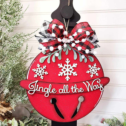 The Jingle Bell Door Hanger by Janet's Craft Corner adds a festive touch to your holiday decor with its red ornament adorned with white snowflakes and the phrase "Jingle all the Way" in cursive. It is completed with a black and white plaid bow, green foliage accents, and a backdrop of snow-dusted greenery.